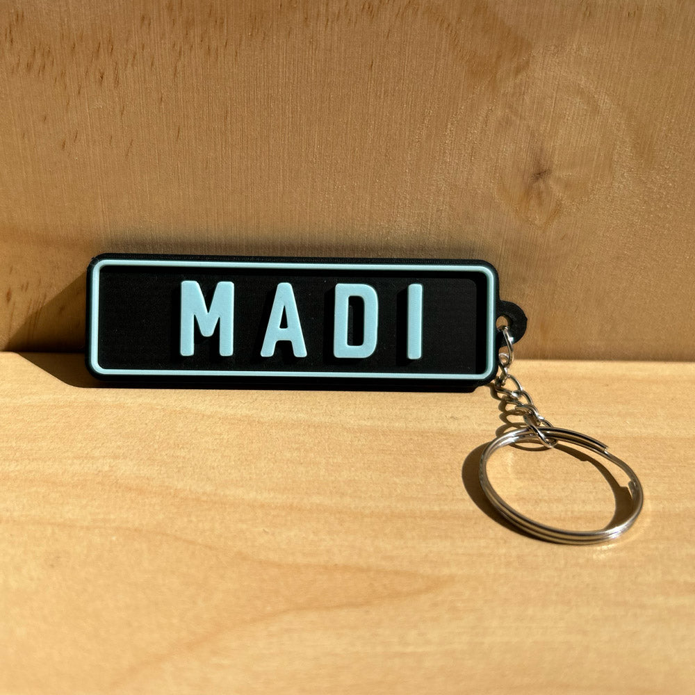 Car Plate Keychain with 'MADI' on a wooden surface