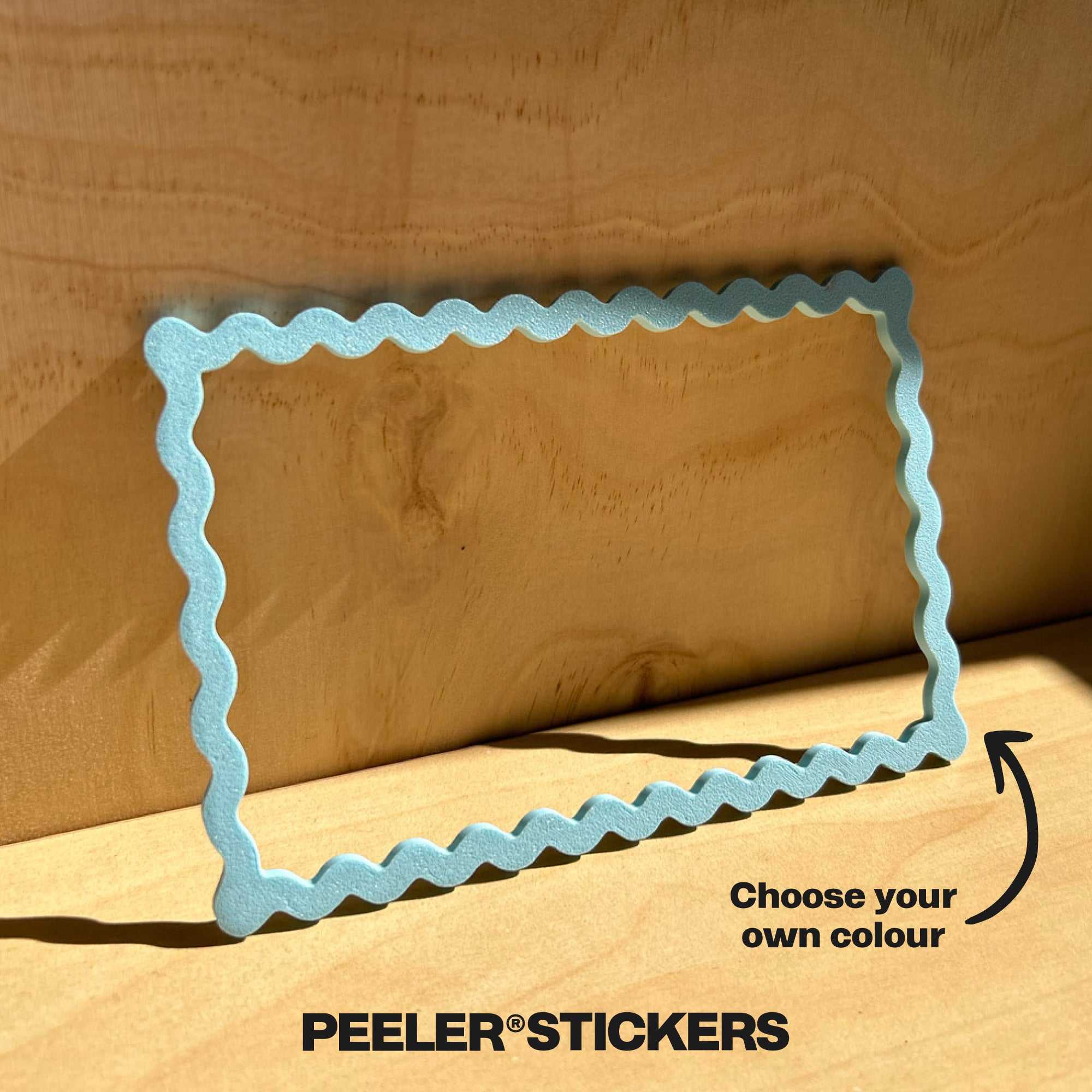 Rectangular blue wavy frame on a wooden background with 'Peeler Stickers' branding.